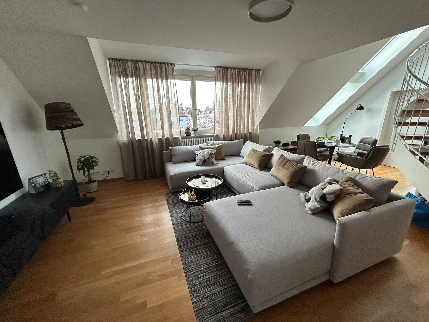 Living and dining area of a penthouse in Karlsruhe with a black spiral staircase