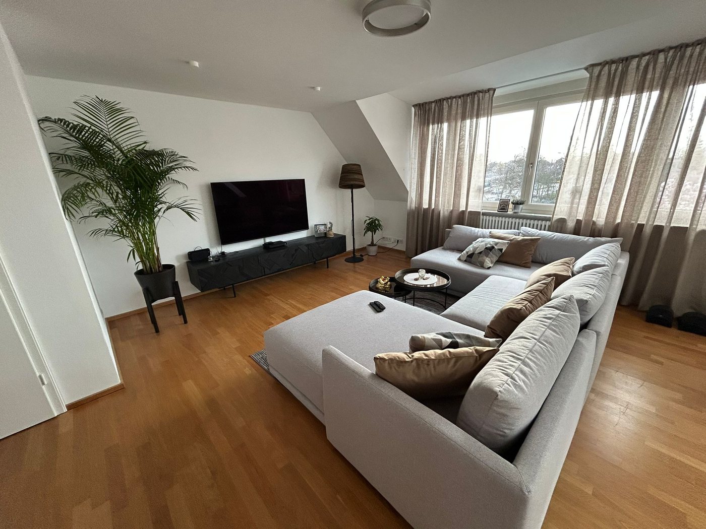 Living area with a light sectional sofa and sloping ceiling
