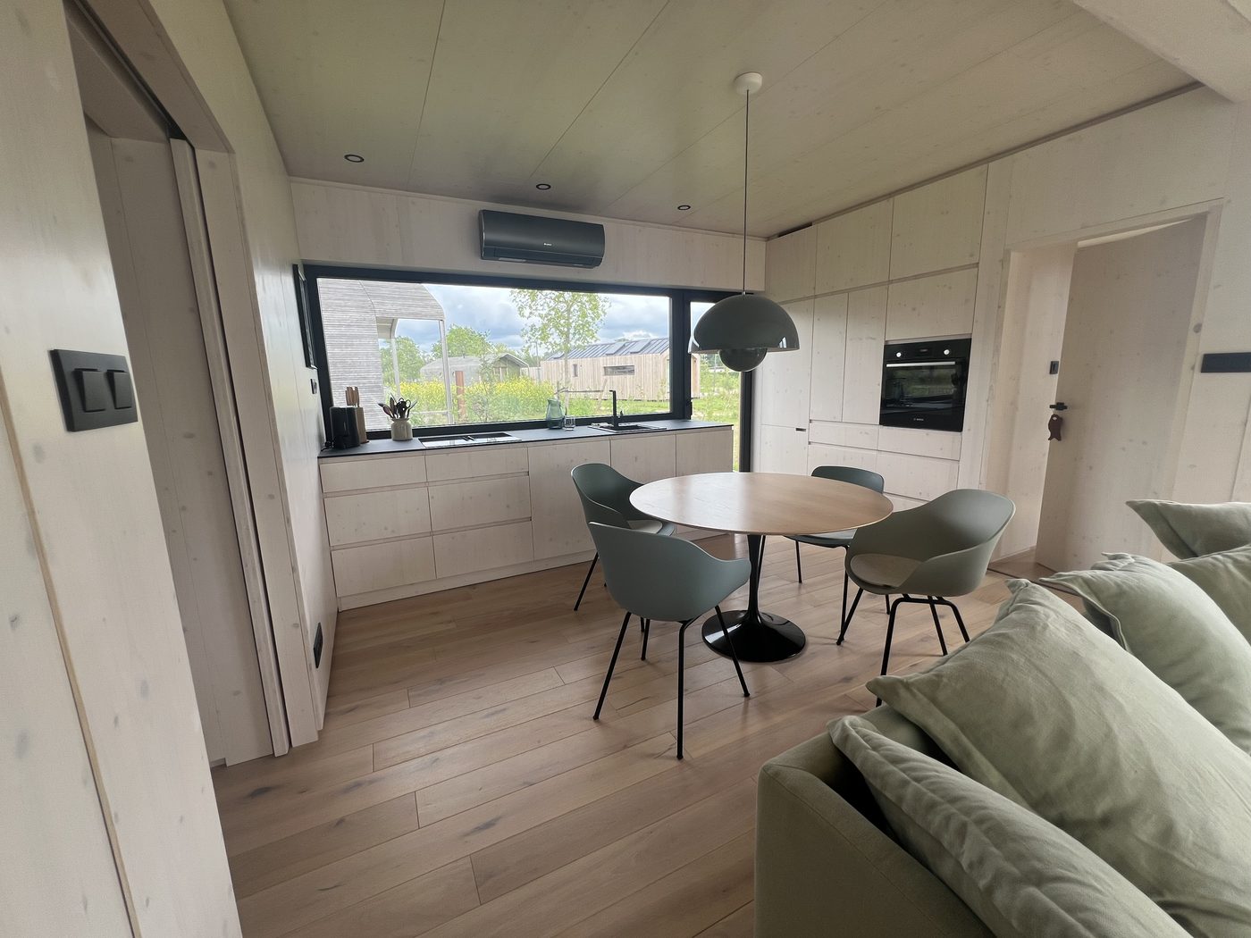 Kitchen run beneath a long strip window and round dining area with shell chairs