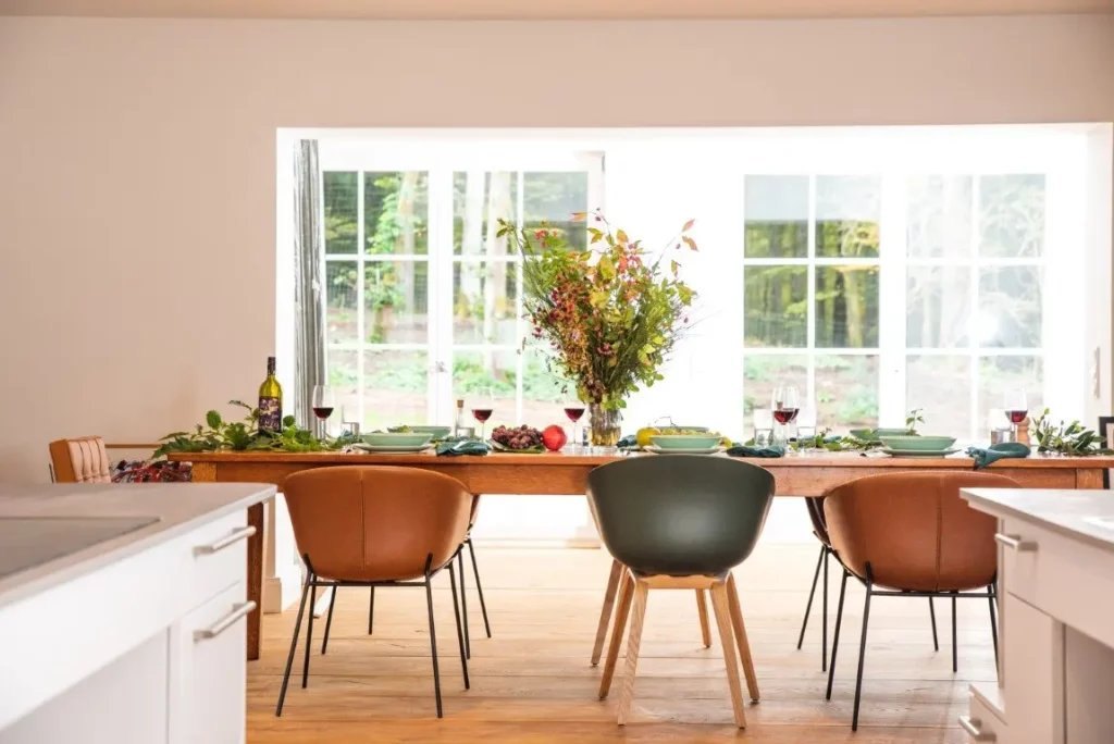 Laid dining table in cognac and grey tones in front of large windows